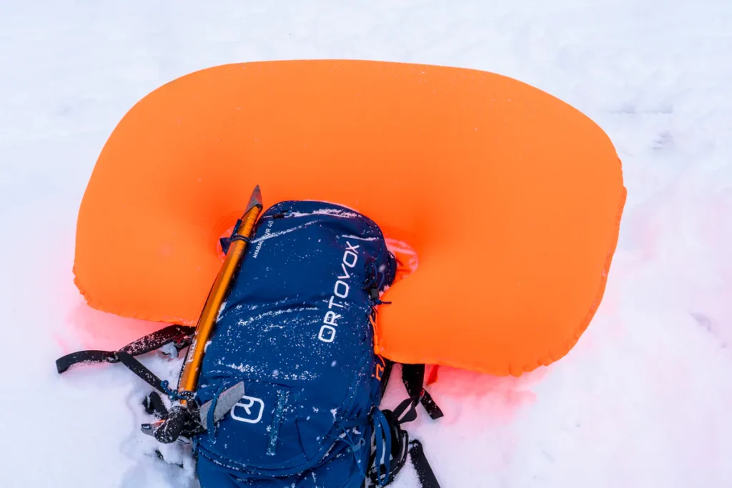 Lyžař aktivuje lavinový batoh airbag v horském terénu pro zvýšení bezpečnosti