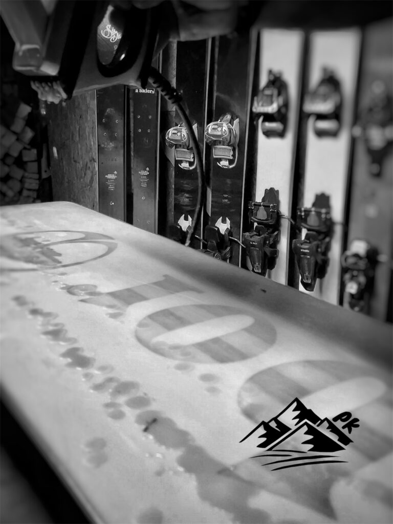 „Ruční voskování lyží žehličkou v Prostekram.cz – čerstvě nanesený vosk na skluznici a připravené freeride lyže v pozadí. Detail domácího servisu, kde vzniká dlouhá výdrž, hladký skluz a precizní příprava lyží pro freeride a skitouring.“